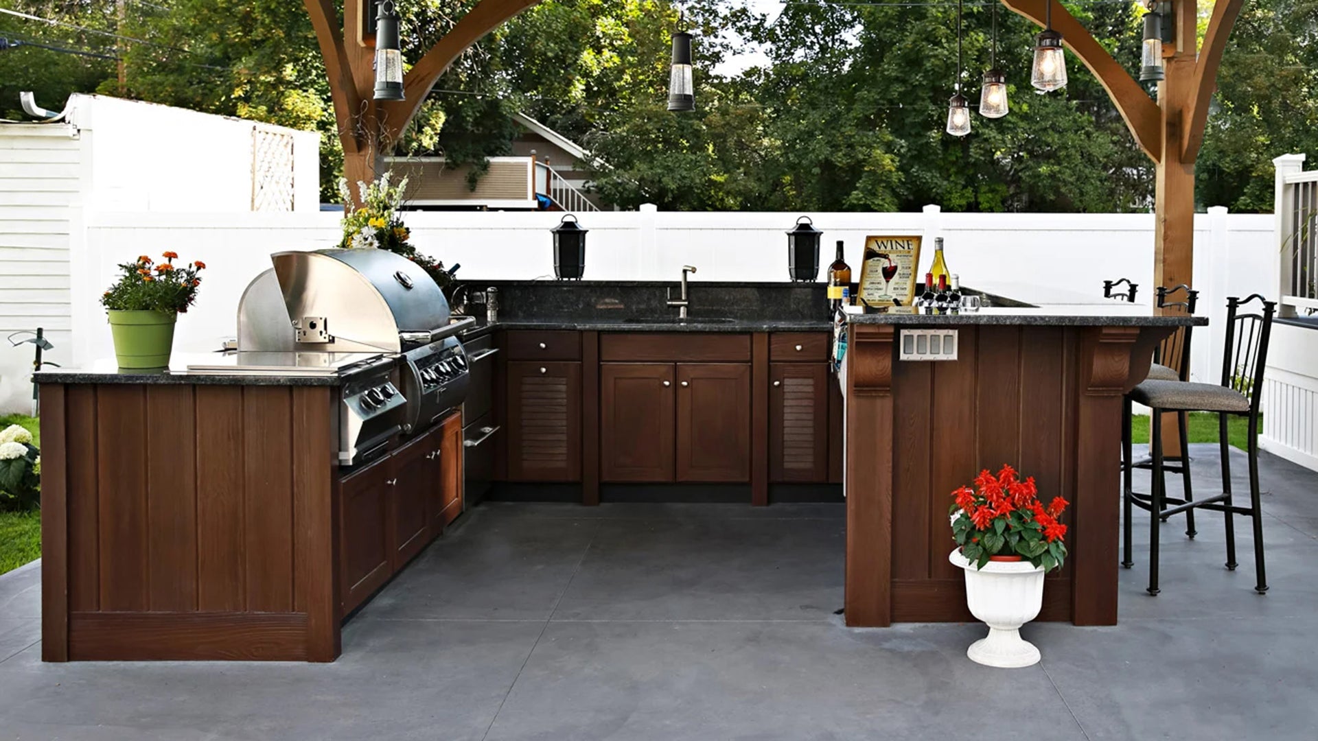 Outdoor kitchen with wooden cabinets, grill, and bar area.