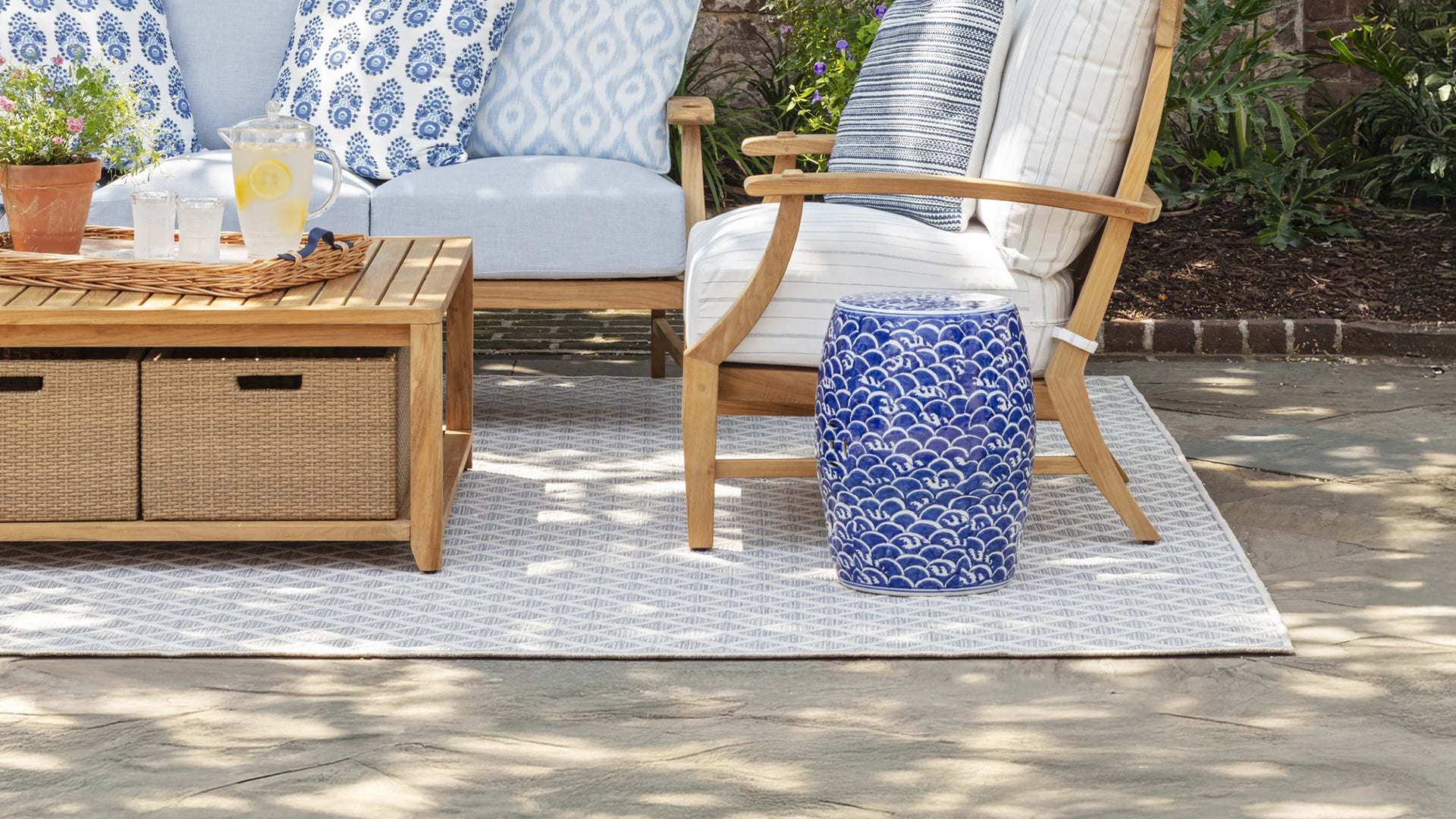 Outdoor patio setting with chairs, table, and blue patterned ottoman.