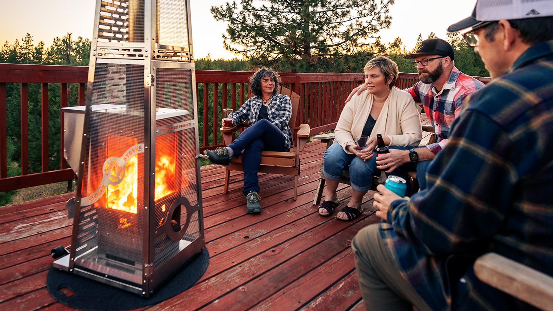 People sitting around a fire pit on a wooden deck with trees in the background