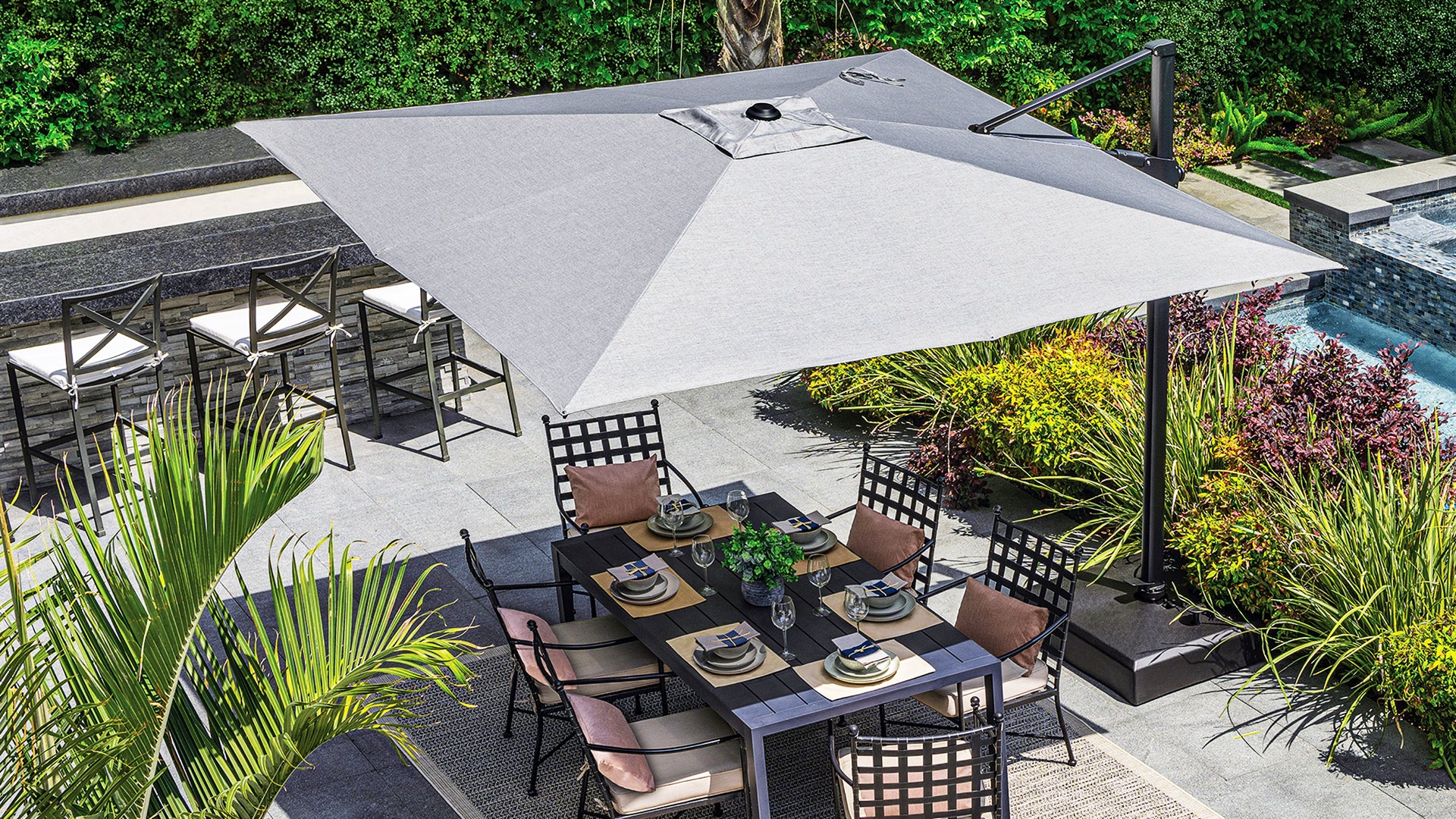 Outdoor patio setup with dining table, chairs, and umbrella in a garden setting.